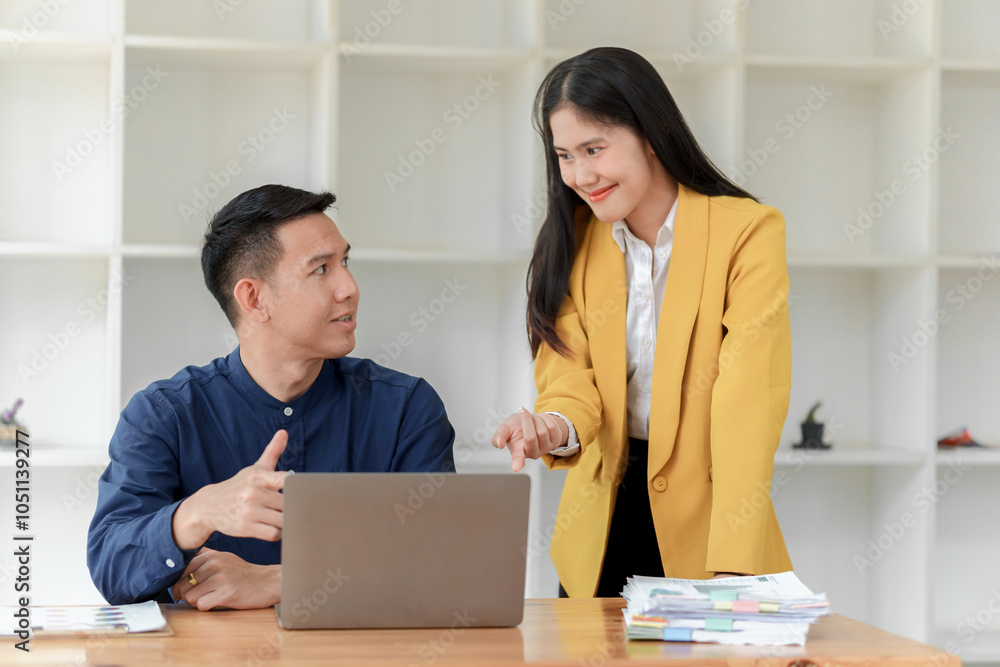 A man and woman engage in a professional discussion at a desk, with a laptop and paperwork present, conveying teamwork and collaboration in a modern office setting. A man and woman engage in a professional discussion at a desk, with a laptop and paperwork present, conveying teamwork and collaboration in a modern office setting.