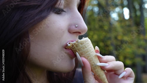 Captured in a close-up, a young girl's happy expression radiates as she seductively licks ice cream.
