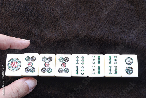 Female hands and Mahjong tiles on the table. Chinese board game, Chinese traditional, tile-based.Blank space for text