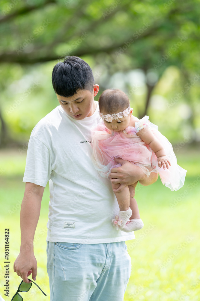 Fototapeta premium A Taiwanese couple in their 20s and their 7-month-old baby celebrate a birthday in a vast green park in Yilan County, Taiwan.