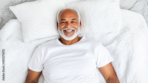 Elderly man with a serene smile lying comfortably on a soft white bed, exuding tranquility and warmth in a peaceful setting. photo