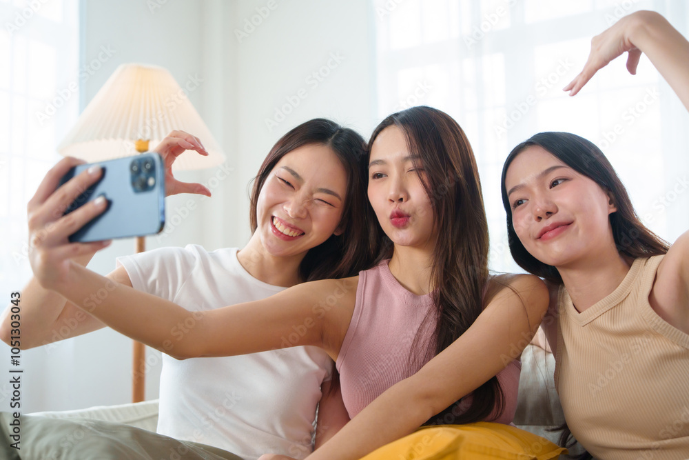 Friendship of Three young women taking a playful selfie together. Smiling teenage girls making funny faces and gestures, enjoying a joyful bonding moment in a living room. Friendship of Three young women taking a playful selfie together. Smiling teenage girls making funny faces and gestures, enjoying a joyful bonding moment in a living room.