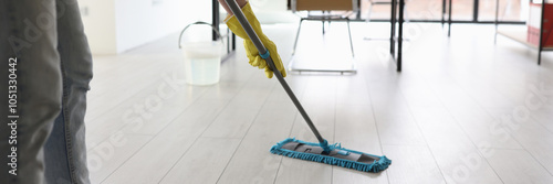 фотографія Woman cleans floor with wet mop in corporate office room