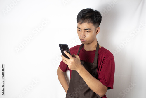 A teenage bartender is surprised by the contents of the message on his cellphone.