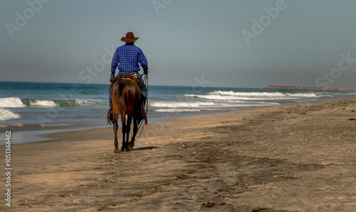 A cowboy riding a horseon the sand at a beach in Rosarito Mexico photo