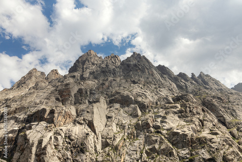 Vertical rugged rocky wall reaching the clouds in the mountains of Ala Archa national park