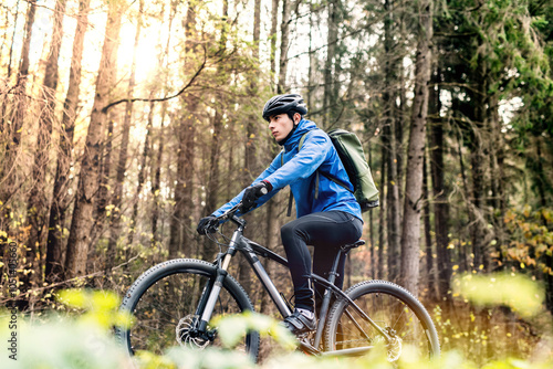 Active man on bike in the middle of beautiful forest, early autumn morning. Concept of healthy lifestyle. Low angle view. photo