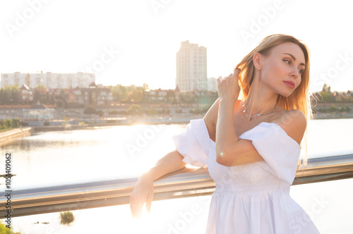 Beautiful young woman walking in sunny city in summer