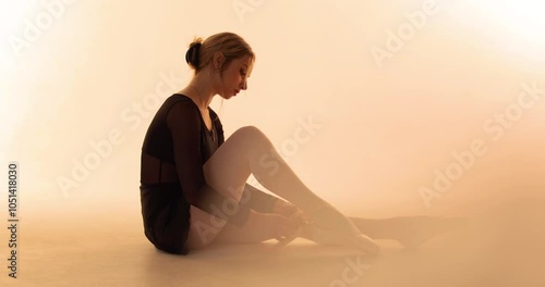 Ballerina dancer puts on pointe shoes in the dance hall preparing for the rehearsal