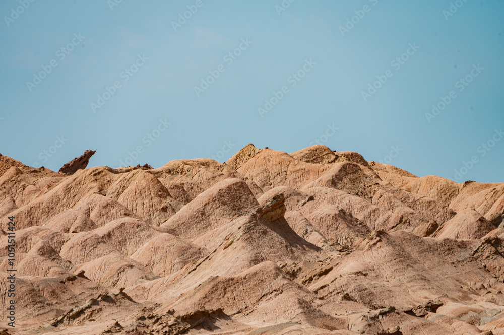 Fototapeta premium A breathtaking aerial view of a rugged desert canyon landscape at golden hour, showcasing dramatic rock formations, sandy terrain, and a winding road under a clear sky
