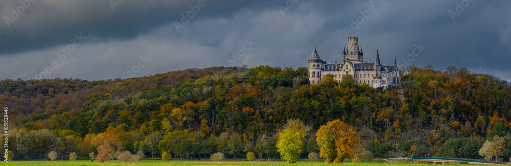 Panoramic view of Marienburg Castle, historic Gothic Revival masterpiece in Lower Saxony, Germany, rising atop a hill, with ornate towers and intricate architecture framed by autumn foliage. Panoramic view of Marienburg Castle, historic Gothic Revival masterpiece in Lower Saxony, Germany, rising atop a hill, with ornate towers and intricate architecture framed by autumn foliage.