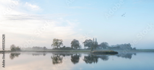 farmhouse reflected in water of river lek near wijk bij duurstede in holland on foggy morning