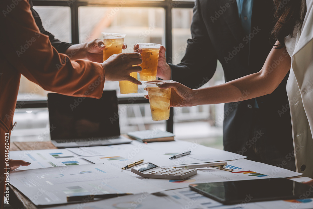 Team of business men and women sitting at desks with documents, graphs, charts, holding glasses of champagne, clinking beers, celebrating a party in business success together in the office. Team of business men and women sitting at desks with documents, graphs, charts, holding glasses of champagne, clinking beers, celebrating a party in business success together in the office.