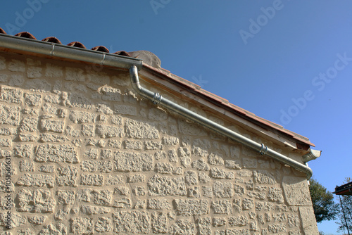 Gouttière en zinc gris sur la façade de la maison en pierre