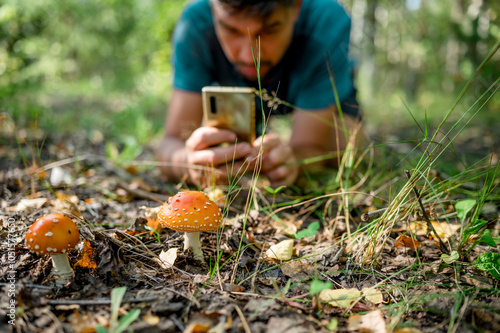 Man photographing mushroom in forest photo