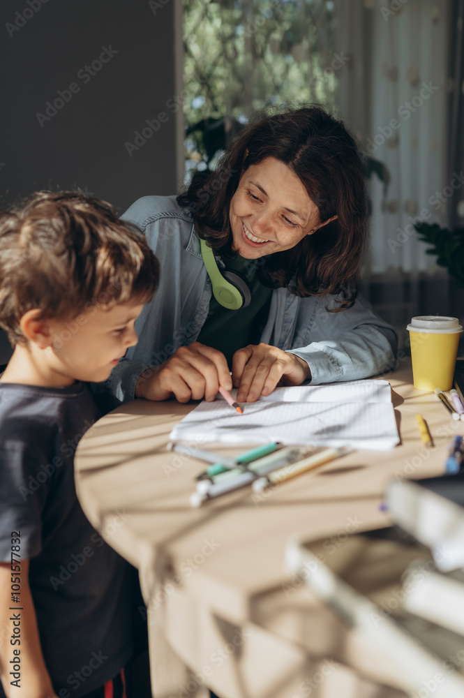 Smiling mother assisting son in doing homework at home Smiling mother assisting son in doing homework at home