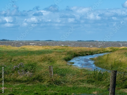Blick über das Naturschutzgebiet Wattenmeer bei Hochwasser und stürmischer See mit einer Nordseeinsel im Hintergrund