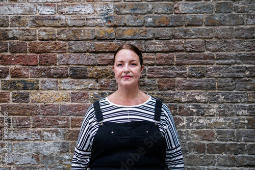 Mature woman standing in front of brick wall photo