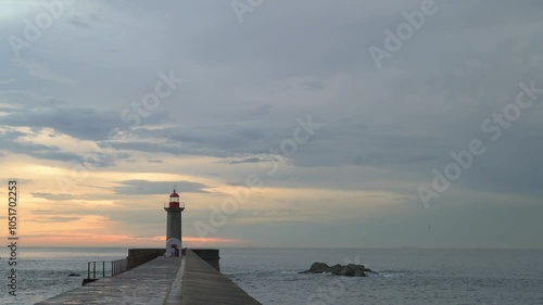 Sunset at the Porto lighthouse. People walking and birds flying.
