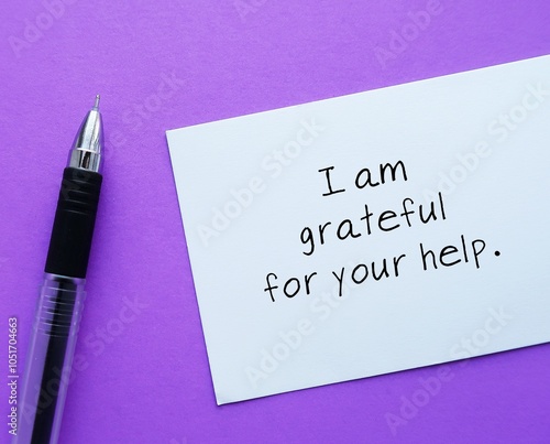 Paper note on purple background with text written - I am grateful for your help - message to thank anyone for their support - write a card of appreciation photo