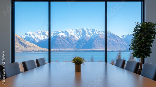 A modern conference room with a wooden table, overlooking stunning snow-capped mountains and a serene lake through large windows. photo