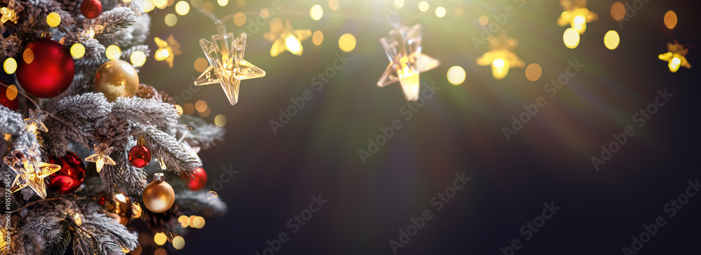 Christmas tree with Christmas balls on the background of the night sky - decorations on fir branches with shiny and unfocused lights and snowflakes on an abstract background