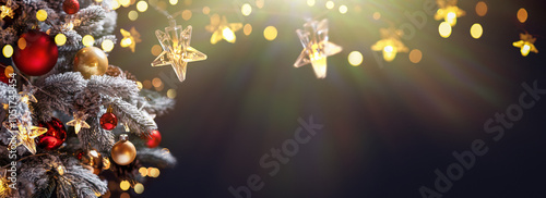 Obraz na płótnie Christmas tree with Christmas balls on the background of the night sky - decorations on fir branches with shiny and unfocused lights and snowflakes on an abstract background w salonie