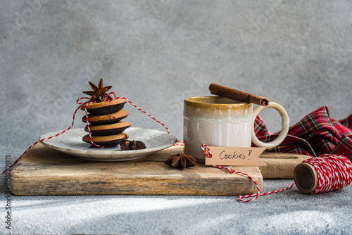 Close-up of a cup of black tea on a wooden chopping board with a stack of tied vanilla chocolate cookies and a gift tag