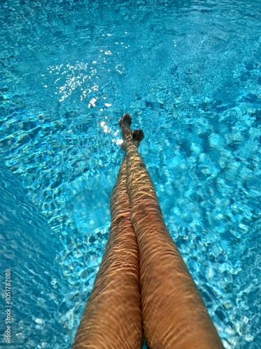 Overhead view of a woman's outstretched legs crossed at ankle in a swimming pool photo