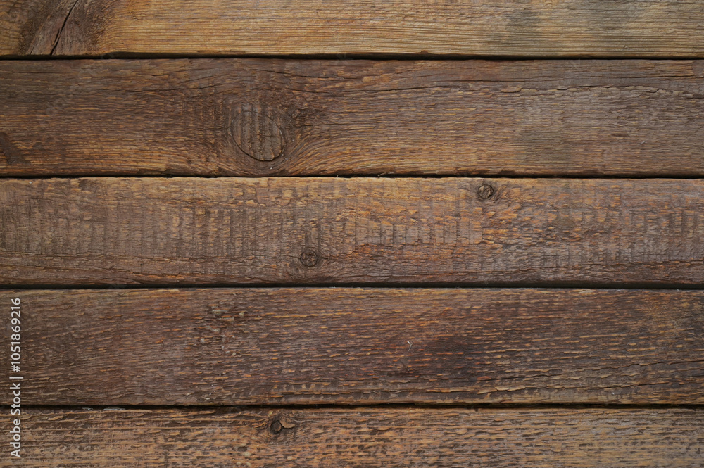 Obraz premium A brown background of wooden boards, with a variety of brown shades. The boards are slightly worn, which adds a sense of naturalness and antiquity. Ideal for backgrounds in designs, advertisements