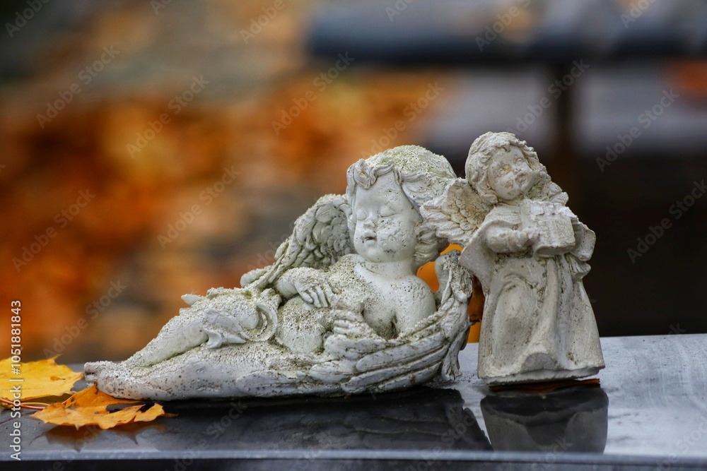 Sleeping angel figure on a grave in autumn with fallen leaves. Sleeping angel figure on a grave in autumn with fallen leaves.