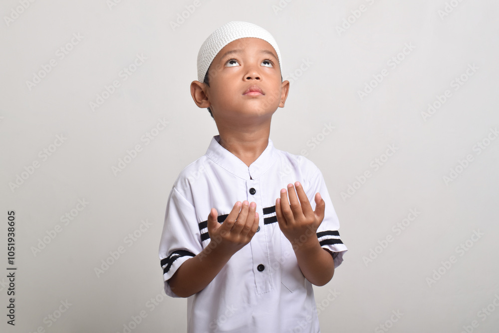 Asian Muslim boy praying with open hands isolated on white background. Praying to God devoutly, praying gesture with hands raised Asian Muslim boy praying with open hands isolated on white background. Praying to God devoutly, praying gesture with hands raised