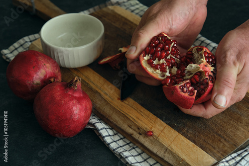 a man breaks open a ripe red pomegranate