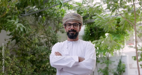 Omani man wearing dishdasha and Musaar is stand folding his arms