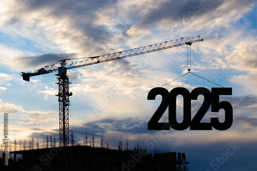 2025 New Year for planning and strategies concept. Silhouette of a construction crane against blue cloudy sky at a construction site raising the number 2025 year. Ideas of development and investment photo