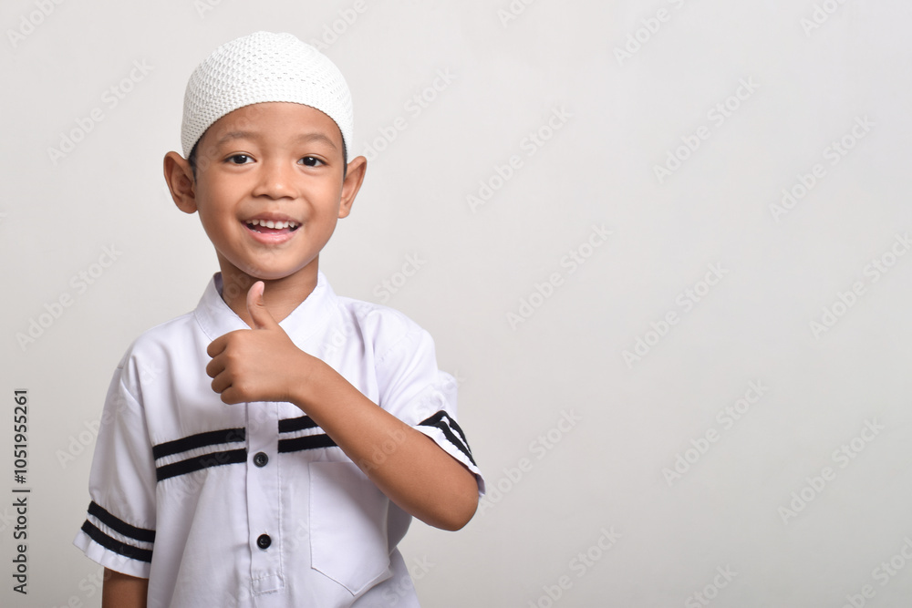 Portrait of a cheerful Asian Muslim boy posing with a thumbs up isolated on a white background Portrait of a cheerful Asian Muslim boy posing with a thumbs up isolated on a white background