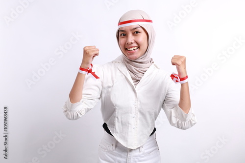 A young Asian muslim woman with a happy successful expression wearing red white flag headband isolated by white background. Indonesia's independence day concept. photo