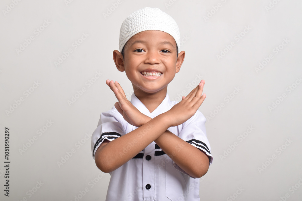 Asian Muslim boy making a cross and showing a refusal expression isolated on white background Asian Muslim boy making a cross and showing a refusal expression isolated on white background