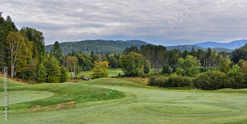 A green golf course among the rolling hills with a cloudy sky on a beautiful summer day in Canada