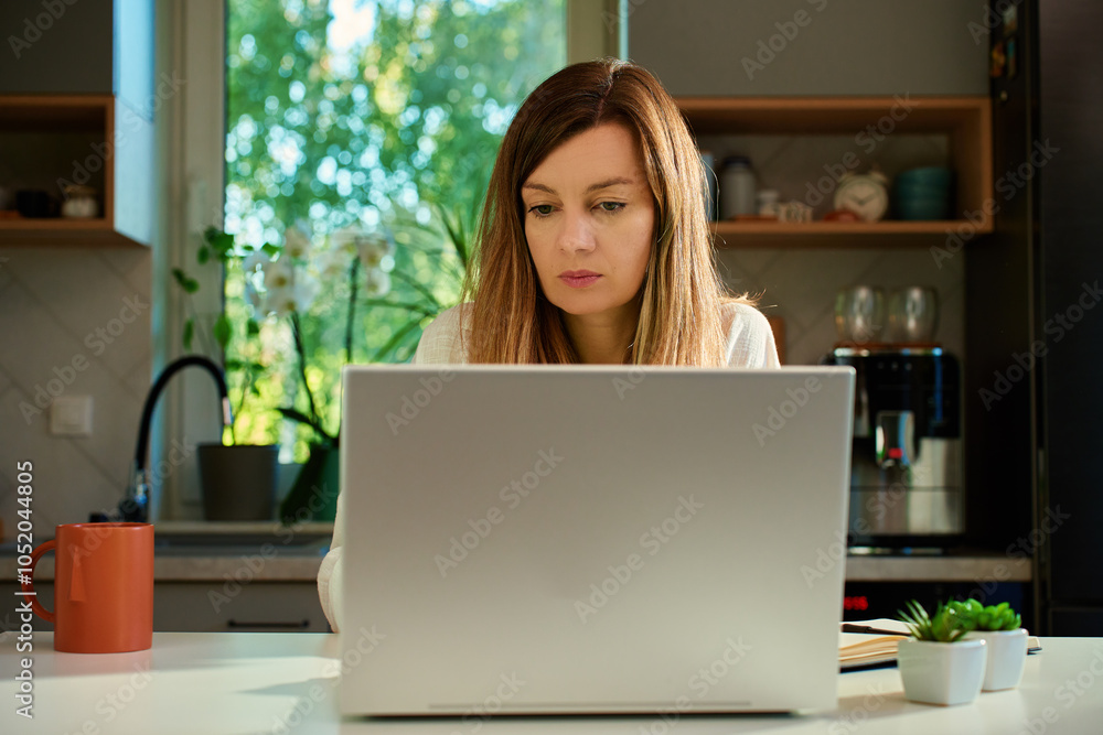Focused woman typing on laptop at home office desk. Millennial freelance woman working remotely. Concept of online distant work Focused woman typing on laptop at home office desk. Millennial freelance woman working remotely. Concept of online distant work