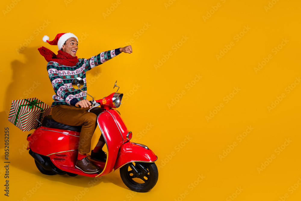 Full size photo of nice young man ride giftbox scooter empty space christmas isolated on yellow color background Full size photo of nice young man ride giftbox scooter empty space christmas isolated on yellow color background