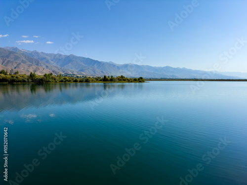 A wooden staircase leading into the clear waters of Issyk-Kul lake, with visible underwater vegetation. A perfect spot for water relaxation and enjoying nature