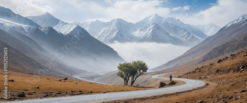 A serene and misty mountain landscape at Salang Pass, with the snow-capped peaks of the Hindu Kush mountain range in the background, a winding mountain road disappearing into the fog. photo