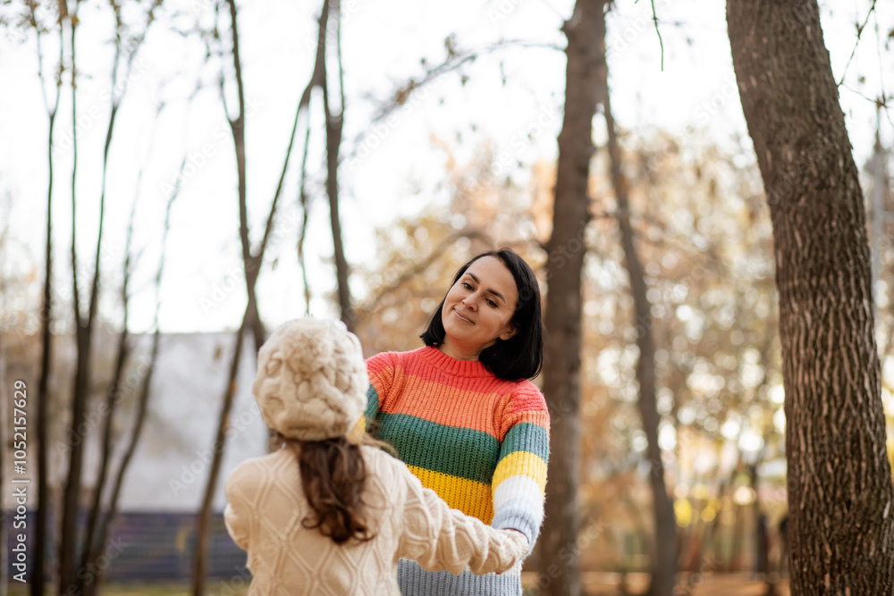 Cute little girl and mom holding hands in the autumn park. Family have fun outdoor. Support and time with family. Cute little girl and mom holding hands in the autumn park. Family have fun outdoor. Support and time with family.