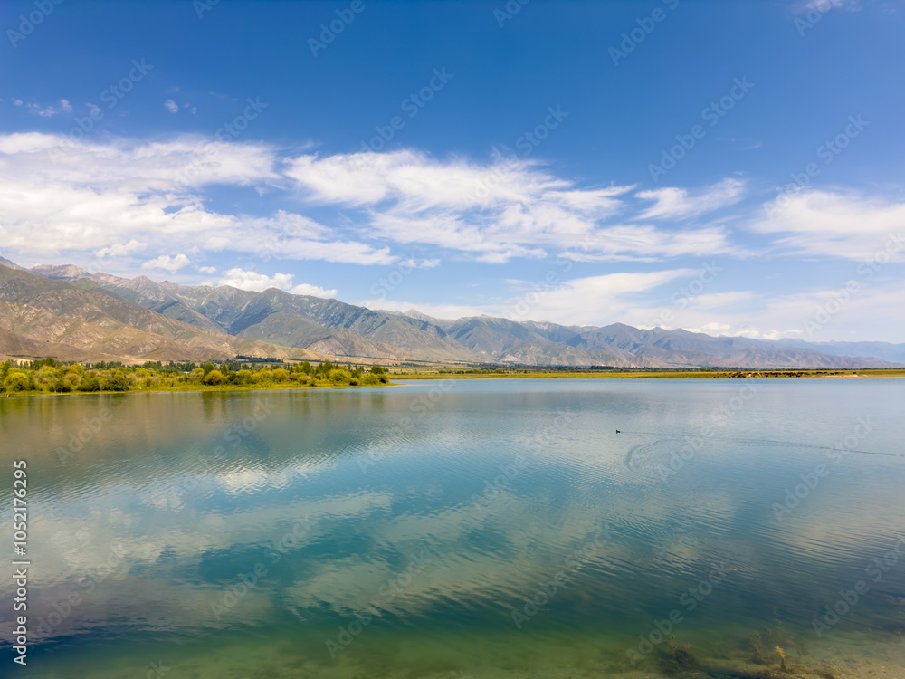 Obraz premium A quiet mountain lake Issyk-Kul, surrounded by green valleys and majestic mountains. The perfect spot for tourism and peaceful relaxation in Kyrgyzstan.