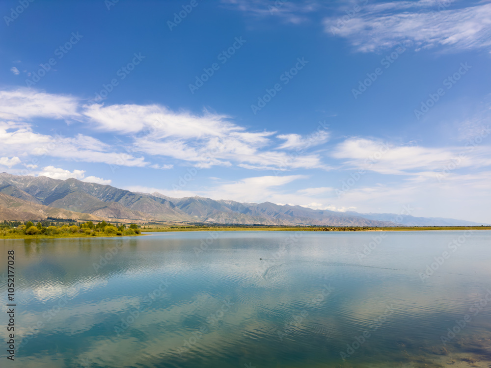 A quiet mountain lake Issyk-Kul, surrounded by green valleys and majestic mountains. The perfect spot for tourism and peaceful relaxation in Kyrgyzstan. A quiet mountain lake Issyk-Kul, surrounded by green valleys and majestic mountains. The perfect spot for tourism and peaceful relaxation in Kyrgyzstan.