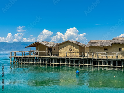 Scenic view of water reflections of Bay of Bones on calm water surface of Lake Ohrid, North Macedonia. Ancient wooden houses built on stilts over the water. Ancient neolithic pile dwelling site photo