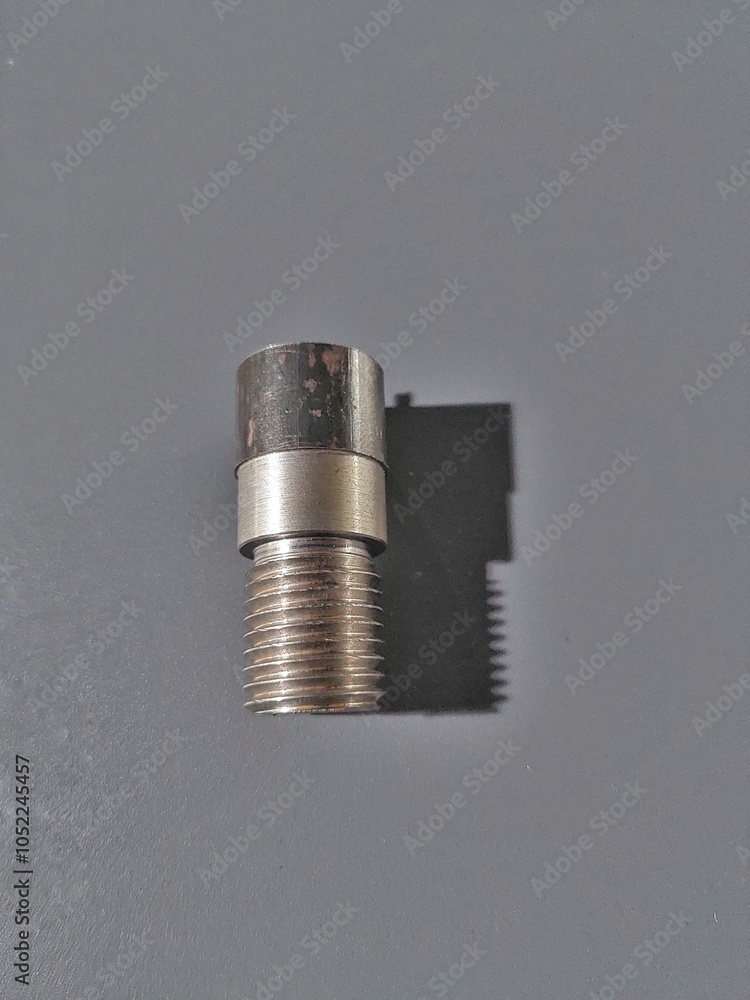 A threaded metal components on a dull blue rough surface A threaded metal components on a dull blue rough surface