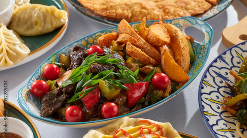 Meat with potatoes and herbs and tomatoes with bell peppers on a white background among other similar Asian dishes