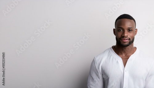 A young black man wearing white clothes in front of white wall